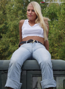Beautiful hot blonde in tight denim jeans is going nude in the forest